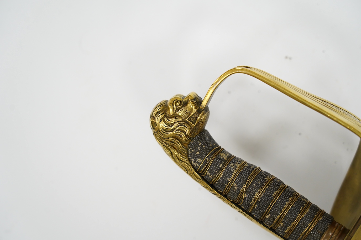 A Victorian warrant officer's sword by Westcott and Sons, regulation brass hilt, black fish skin covered grip, in its brass mounted leather scabbard, blade 79.5cm. Condition - well worn